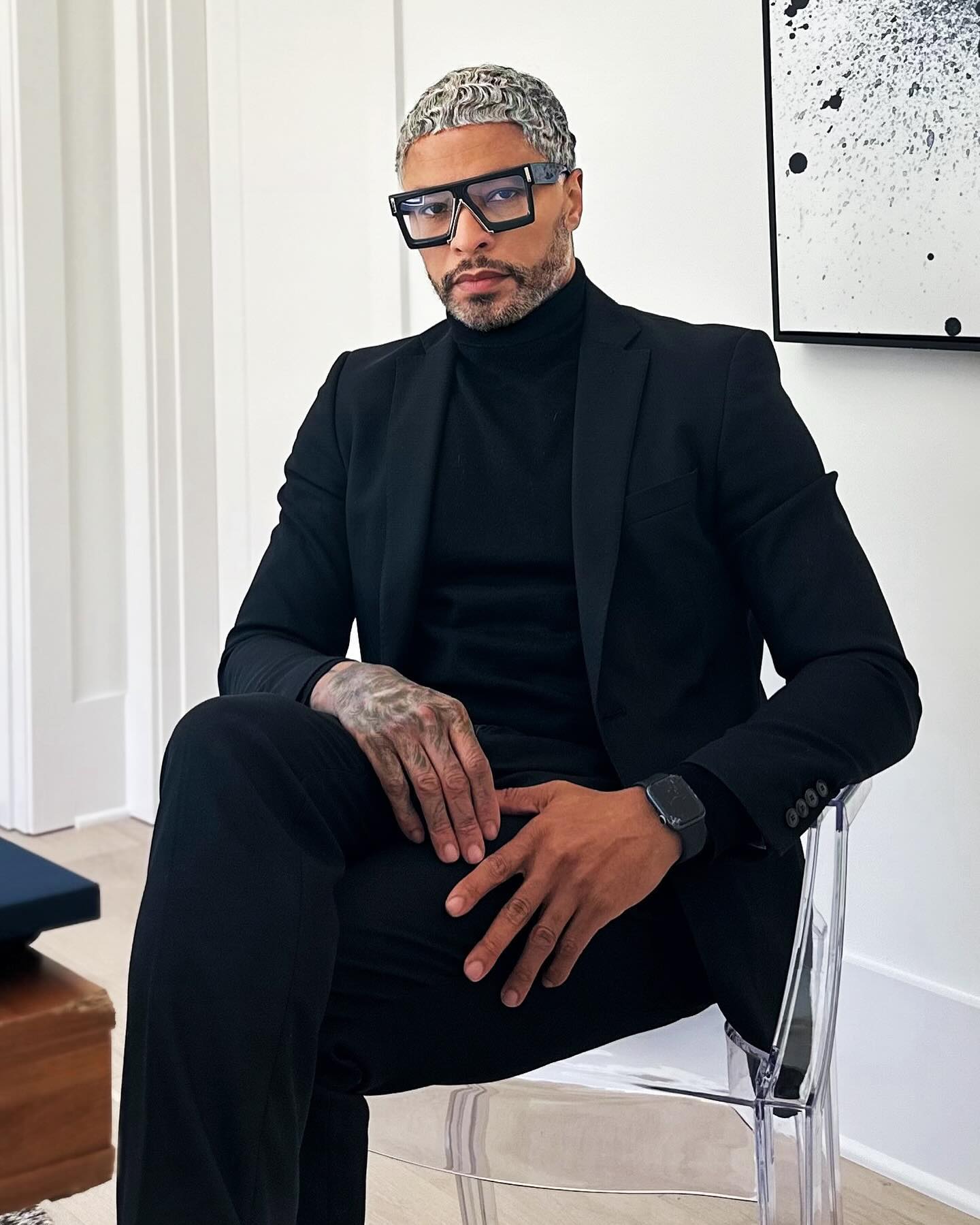 Man in black suit and bold eyeglasses